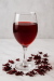 Glass of homemade hibiscus wine with dried hibiscus petals on a table